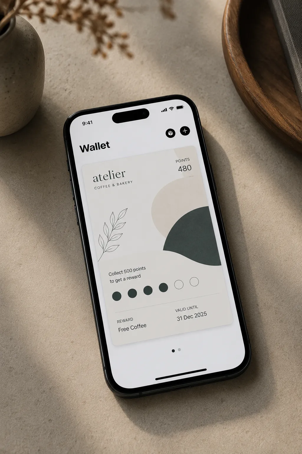 Un iPhone posé sur un comptoir affiche la carte de fidélité d’un café-boulangerie dans Apple Wallet